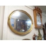A reproduction gilt framed bevelled oval wall mirror - 56cm X 46cm