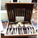 A polished wood canteen containing a six place setting of modern bronze cutlery with stylised bamboo