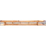 A 3.05m vintage stained pine gymnasium form, set on shaped standard ends