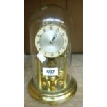 A vintage Koma brass anniversary clock under glass dome