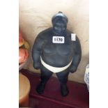 A vintage pottery model of a sumo wrestler in black glaze with white highlighting