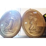 A pair of gold painted cast plaster oval wall hangings depicting Greek goddesses