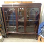 A 1.21m early 20th Century polished walnut display cabinet with blind fretwork decoration to top and