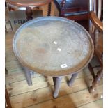 A 59cm diameter Benares brass tray top table with typical decoration, set on a decorative bobbin and