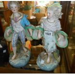 A pair of large Continental porcelain figurines, depicting a girl and boy carrying baskets -
