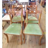 A set of four reproduction yew wood framed sabre leg dining chairs with upholstered drop-in seats