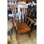 An old elm and beech Windsor high lath back elbow chair with solid elm moulded seat, set on turned