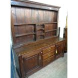 A 1.77m late Georgian oak two part dresser with fluted cornice to multi-shelf open plate rack over a