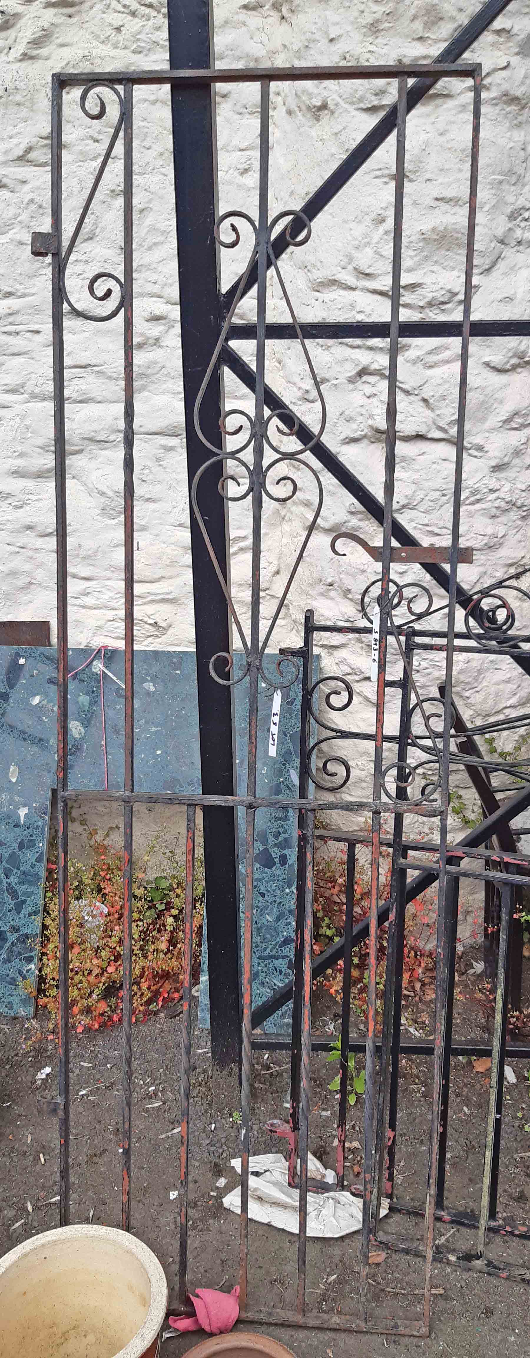 A tall wrought iron side pathway gate