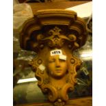 A Victorian stoneware brickwork wall shelf depicting a maiden's head with Rococo scroll decoration