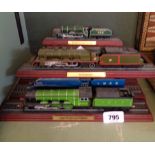 Eight named plastic model locomotives including Mallard and Flying Scotsman, all on polished wood