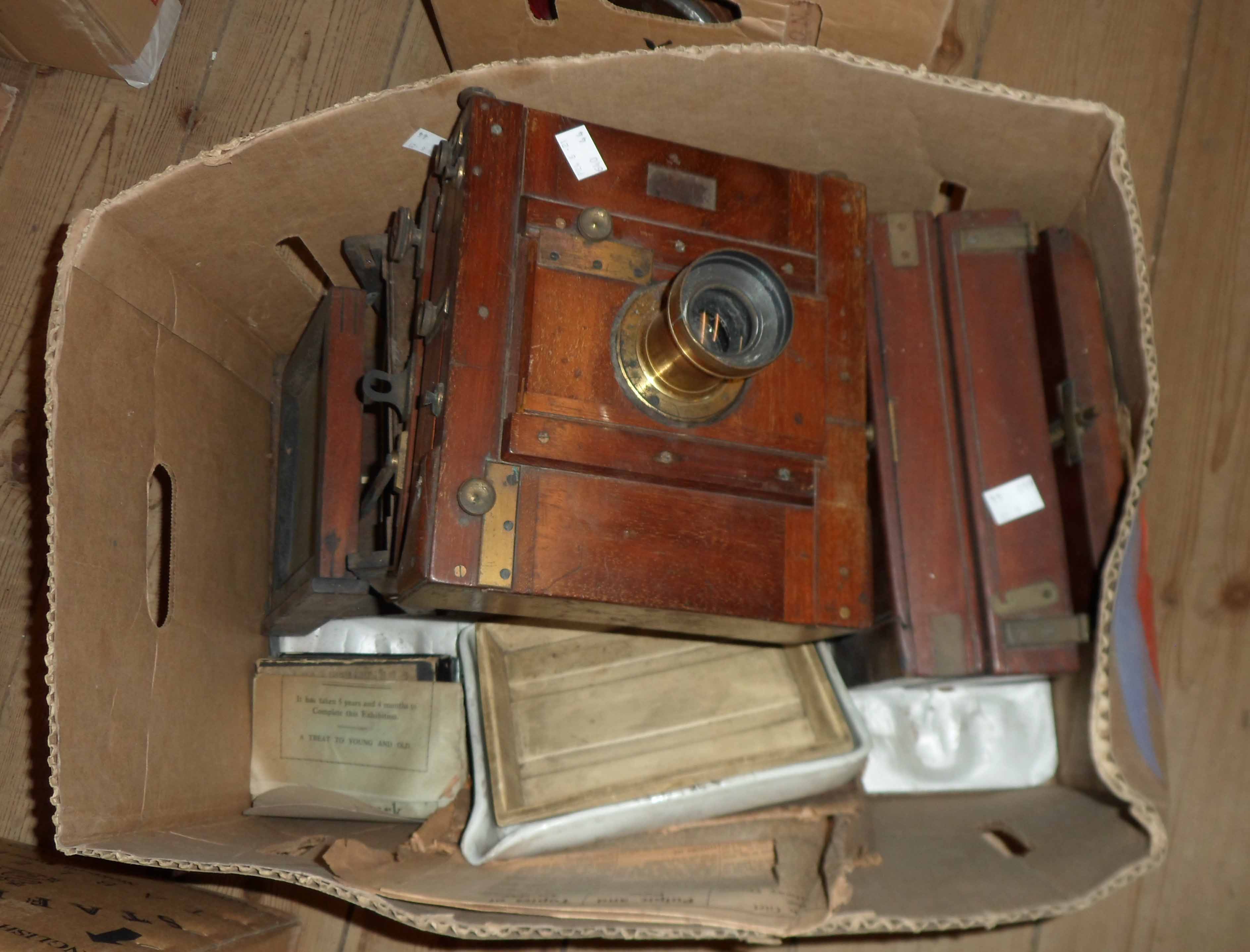 A box containing three antique box camera bodies and other old photographic items