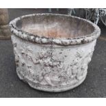 A large concrete round garden planter with classical frieze decoration