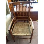 An early 20th Century stained beech framed transitional elbow chair with shaped top rail, flanking