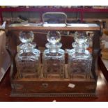 An early 20th Century oak tantalus with three square form spirit decanters with a locking frame,