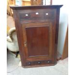 An 83cm late Georgian stained oak wall hanging corner cupboard with shelves enclosed by a panelled