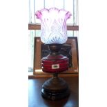 A 19th Century oil lamp with double burner, cranberry glass cut faceted reservoir, brass mounts