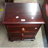 A 45cm modern stained pine and mixed wood bedside chest of three drawers, set on bun feet