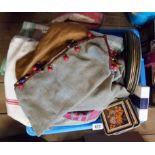 A crate containing assorted textiles including placemats, napkin sets, tablecloths, linen tea