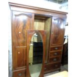 A 1.8m Edwardian flame mahogany veneered and strung triple wardrobe with central bevelled oval