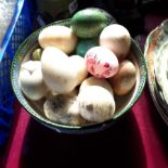 A ceramic bowl containing a quantity of onyx and other hardstone eggs