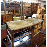 A pair of old stained beech framed pierced ladder back standard chairs with remains of woven rush