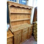 A 1.2m modern pine two part dresser with two shelf open plate rack over a base with three frieze