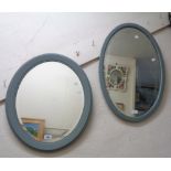 Two painted framed bevelled oval wall mirrors