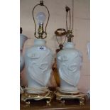 A pair of ceramic lamps moulded with Art Nouveau style flowers on brass bases