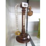 A 23.5cm high Victorian stained wood desk weather station with fluid filled glass tube and further