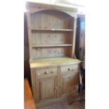 A 1.10m modern pine two part dresser with two shelf open plate rack over a base with two frieze