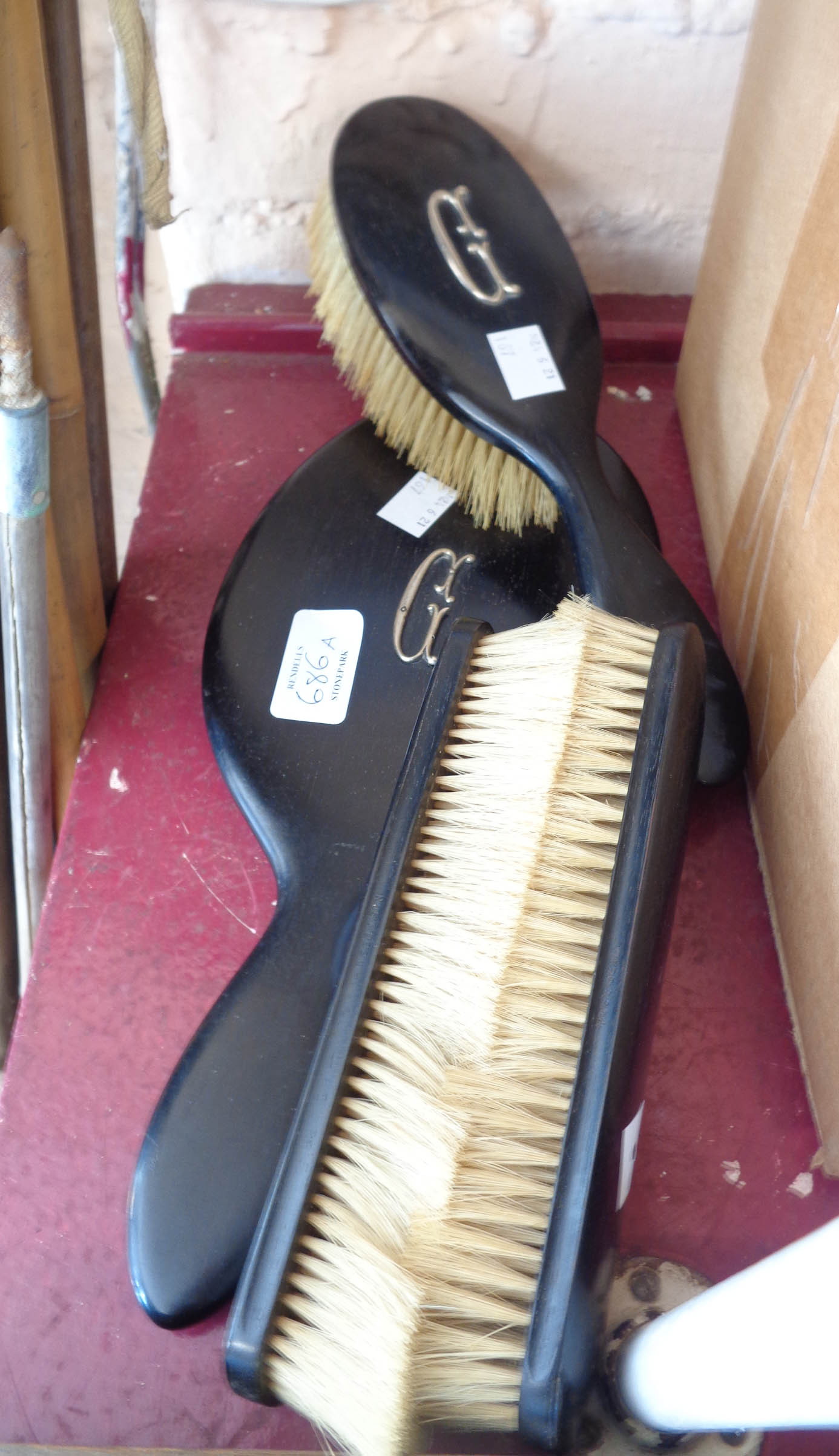 An early 20th Century ebonised part dressing table set comprising a mirror and three brushes -