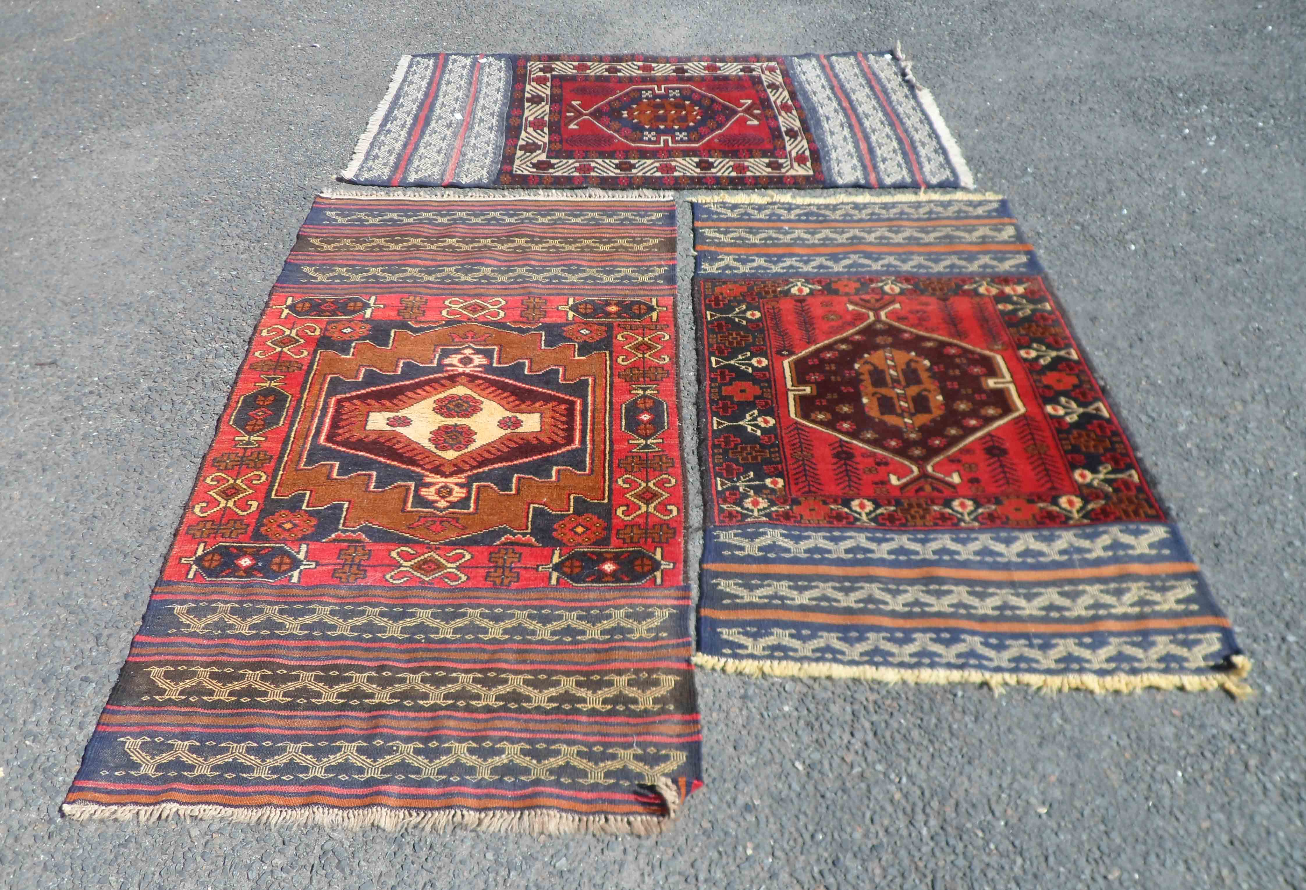 Three Middle Eastern small handmade mats each with central medallion and geometric border, flanked