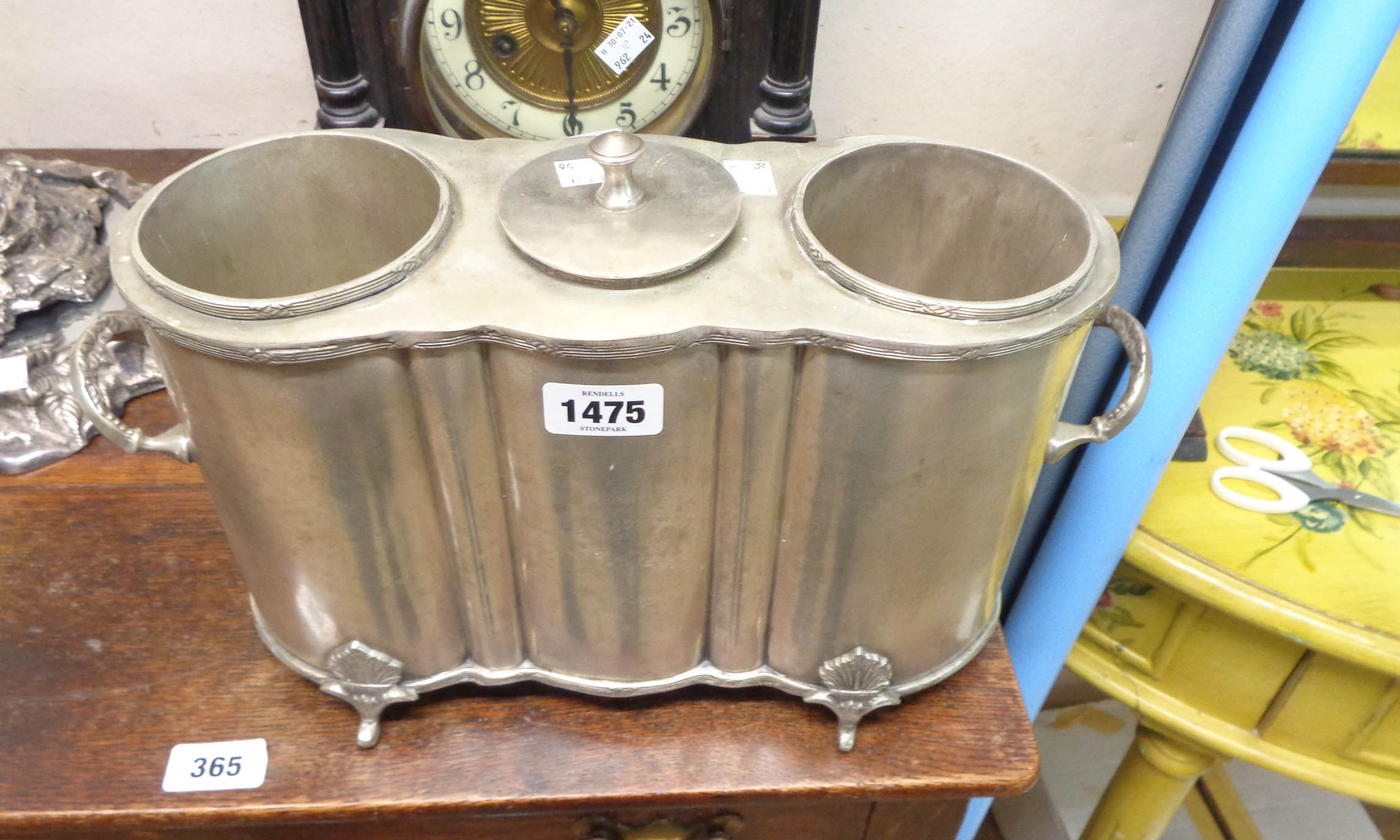 A silver plated two bottle wine cooler with central lidded ice well and flanking handles, set on fan