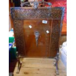 A coppered brass and iron fire screen with beaten effect decorative border and Rococo style handle