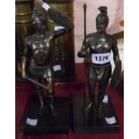 A pair of cast metal statues depicting Roman soldiers with bronzed finish