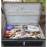 A black japanned tin box containing a quantity of assorted tools, including spanners, screwdrivers