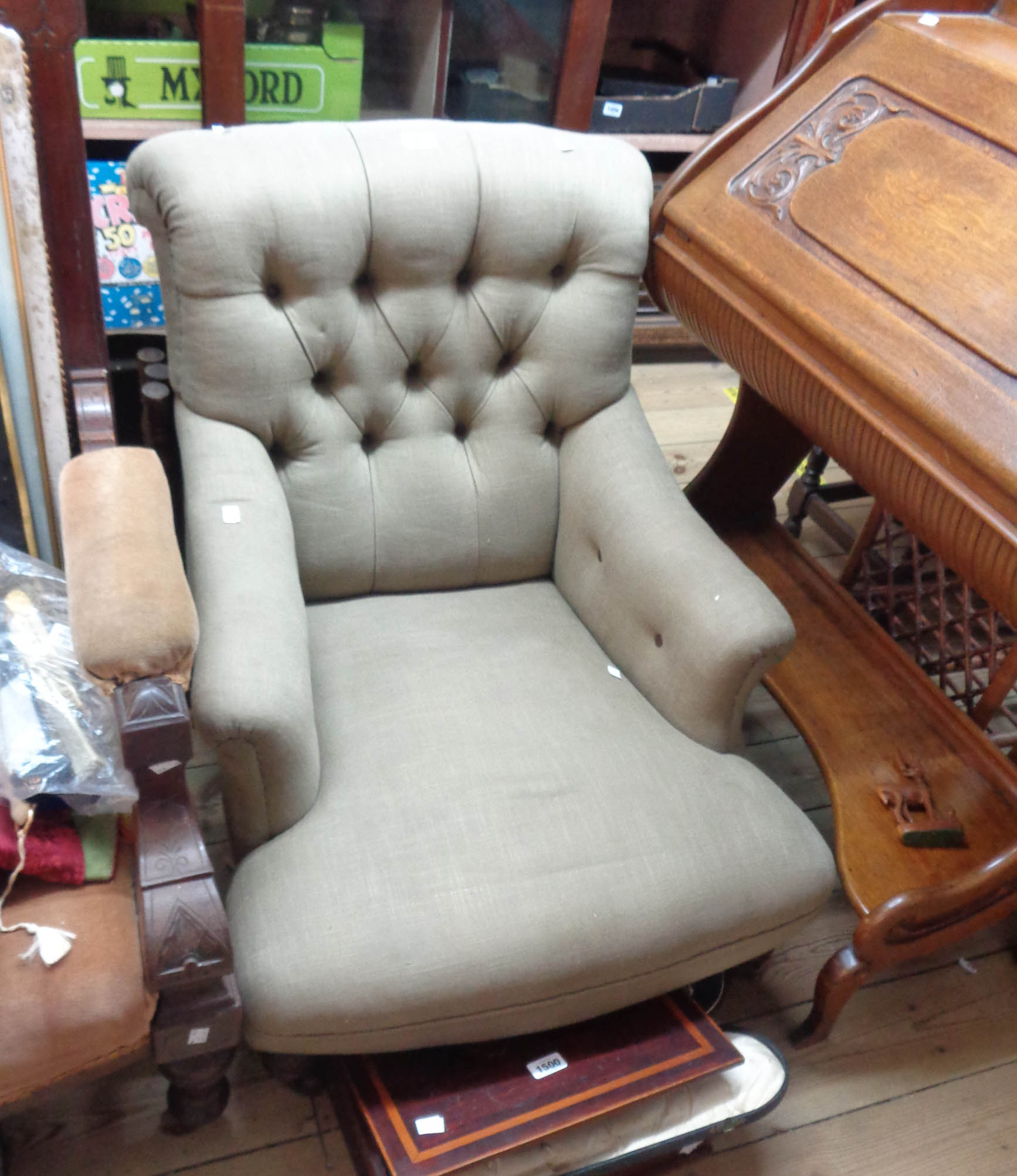 A late Victorian low armchair with button back green cotton upholstery, set on turned front legs and