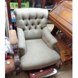 A late Victorian low armchair with button back green cotton upholstery, set on turned front legs and