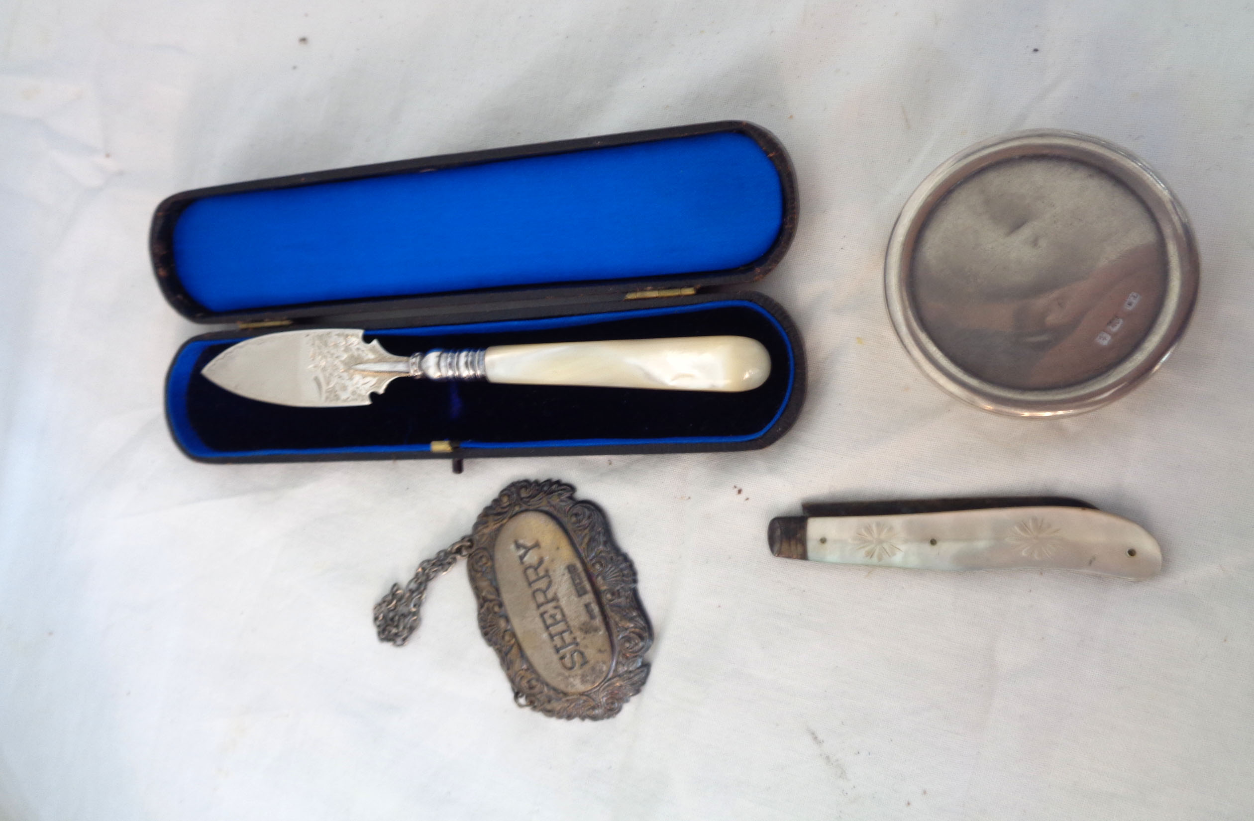 A cased silver ornate butter knife and folding fruit knife both with mother-of-pearl handles -