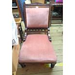 An Edwardian walnut part show frame nursing chair with old rose velour upholstery, set on turned