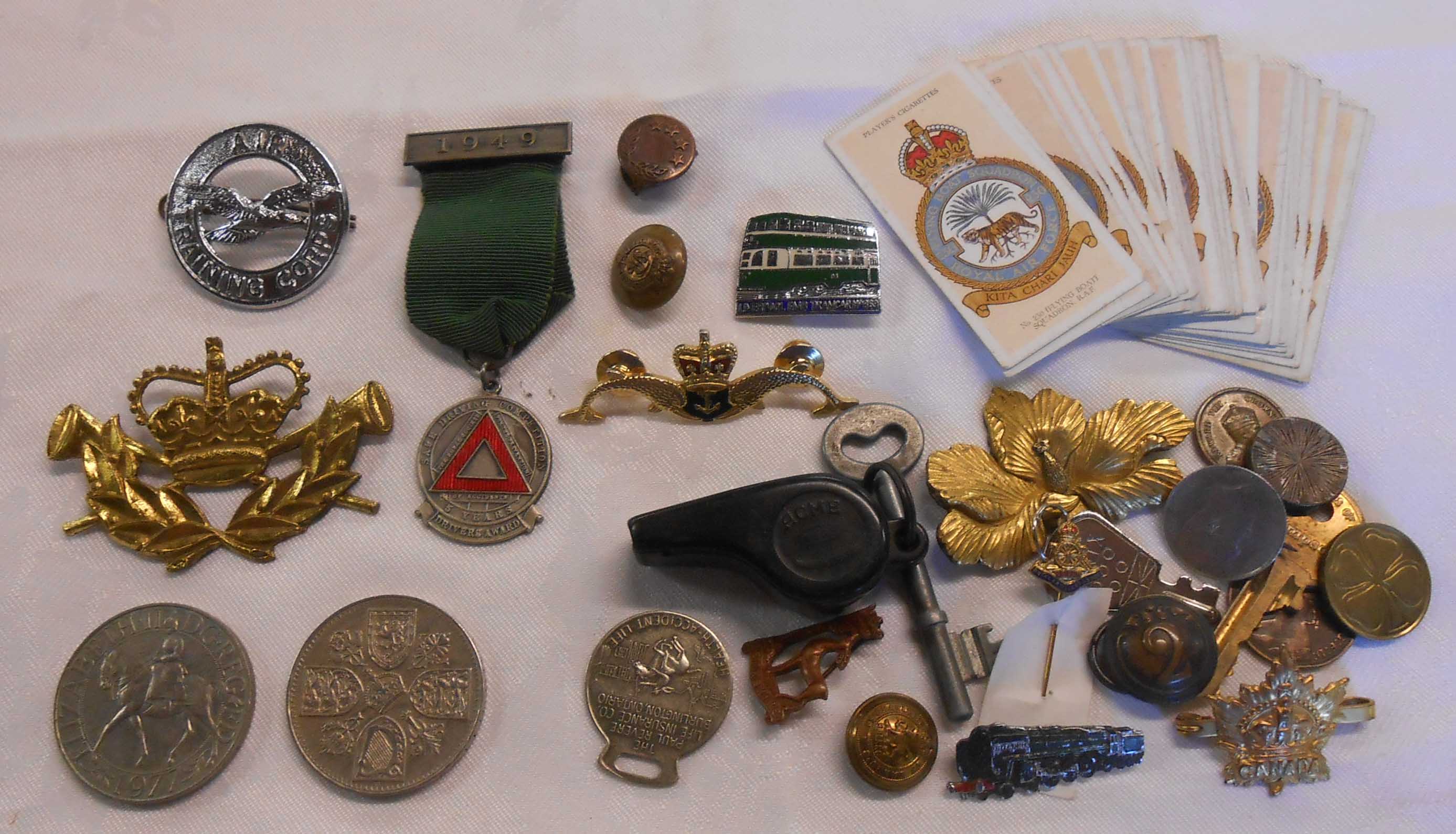 A small tin containing an assortment of military and other badges, crowns, etc.