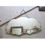 A vintage frameless wall mirror with decorative cut border to shaped plate