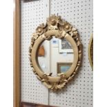 A small reproduction antique style gilt framed wall mirror with floral decoration and circular