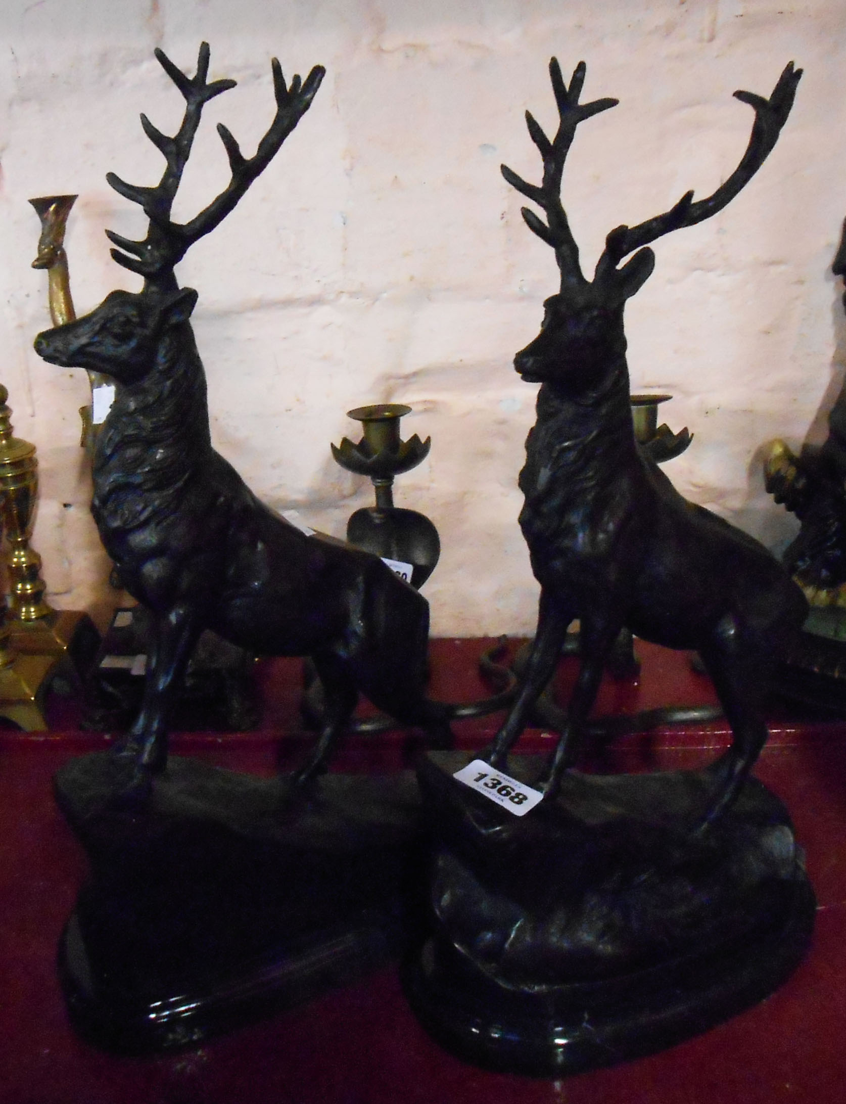 A pair of modern bronze stag figures on a grassy mound set on marble plinths - signature to base