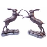 A pair of modern cast bronze figurines of boxing hares on polished marble plinths