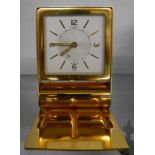 A polished brass folding cased Le Coultre travelling alarm clock with time set pointer to centre