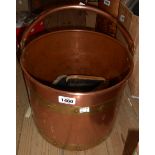 A copper coal bucket with brass banding containing a selection of vintage clothes brushes
