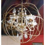 A modern hanging chandelier light fitting with glass sconces and drops, metal frame enclosed in