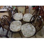 A set of four Ercol dark elm fleur de lys hoop stick back dining chairs with solid moulded seats,